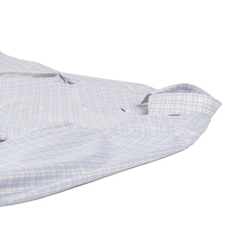 A close-up of a long-sleeve button-up shirt laid flat on a white background, featuring a light blue and white plaid pattern with thin orange and yellow lines.