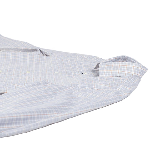 A close-up of a long-sleeve button-up shirt laid flat on a white background, featuring a light blue and white plaid pattern with thin orange and yellow lines.