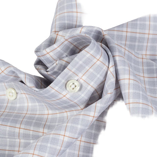 Close-up of a light gray plaid shirt fabric with thin orange-brown grid lines and white buttons.