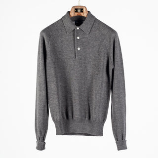 Drake's grey long sleeve merino knit polo shown front on, hanging on a wooden hanger against a pale grey backdrop.