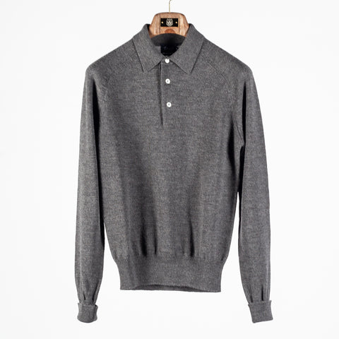Drake's grey long sleeve merino knit polo shown front on, hanging on a wooden hanger against a pale grey backdrop.