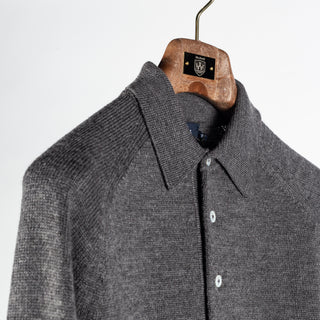 Drake's grey long sleeve merino knit polo at an angle, showing the knitted collar and three-button placket.