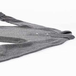 Drake's grey long sleeve merino knit polo laid folded on a pale surface, showing the sleeve and hem.
