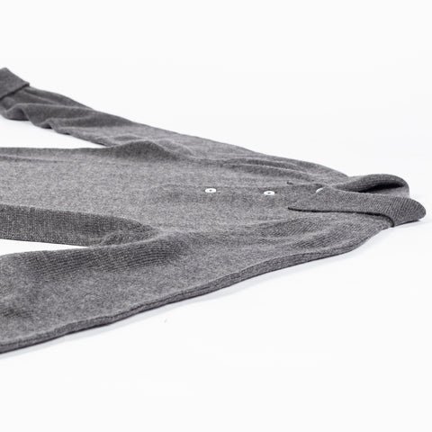 Drake's grey long sleeve merino knit polo laid folded on a pale surface, showing the sleeve and hem.