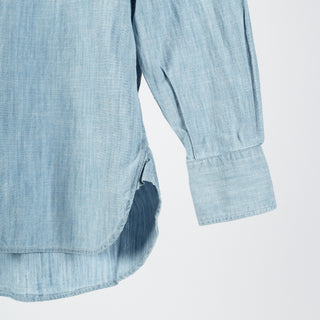 Drake's light blue chambray button-down shirt from the side, showing the sleeve, barrel cuff and curved hem.