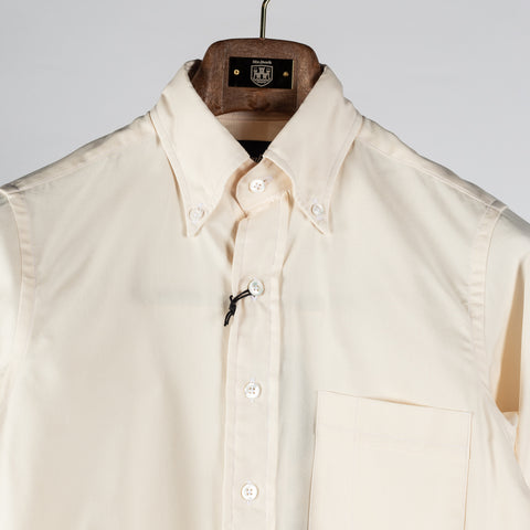 Drake's ecru pinpoint oxford button-down shirt in close up, with the collar points buttoned down over the placket.