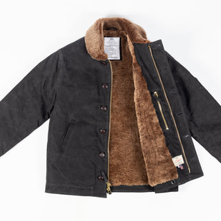Black/Kodiak waxed canvas N-1 Deck Jacket with brown Kodiak mouton collar, open, showing the Kodiak mouton lining, zipper and label