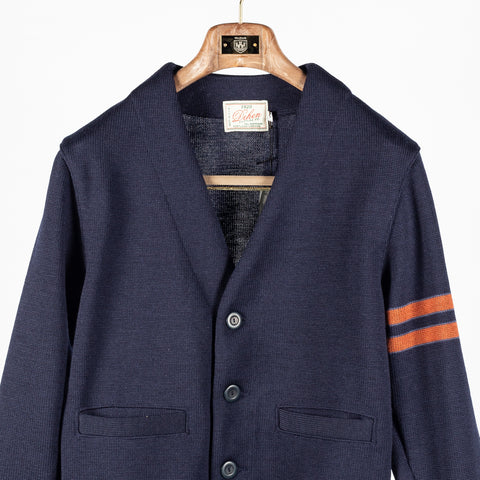 Dark navy wool Slouchy Varsity Cardigan with burnt orange sleeve stripes, front, close view of the buttons and pockets